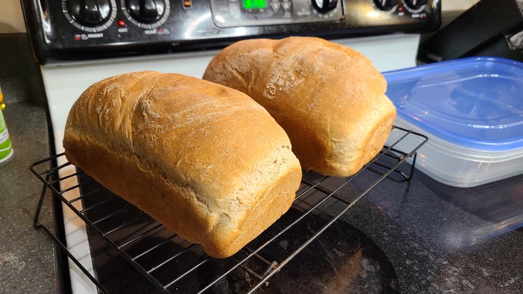 2 loaves of bread resting on a cooling rack