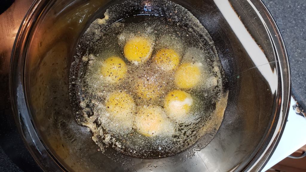 A large bowl with cracked eggs and garlic powder