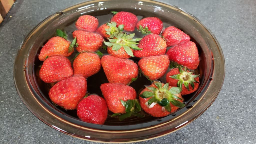 A bowl of strawberries soaking in water and vinegar