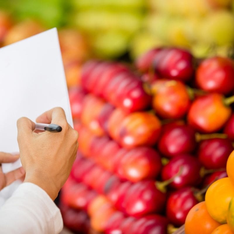 Image of a hand writing on a piece of paper in a grocery store