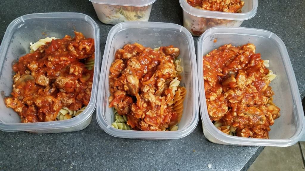 Containers filled with cooked pasta and meat sauce