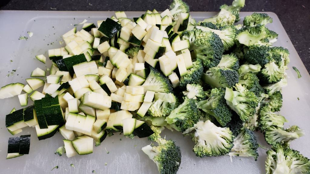 A cutting board with chopped zucchini and broccoli
