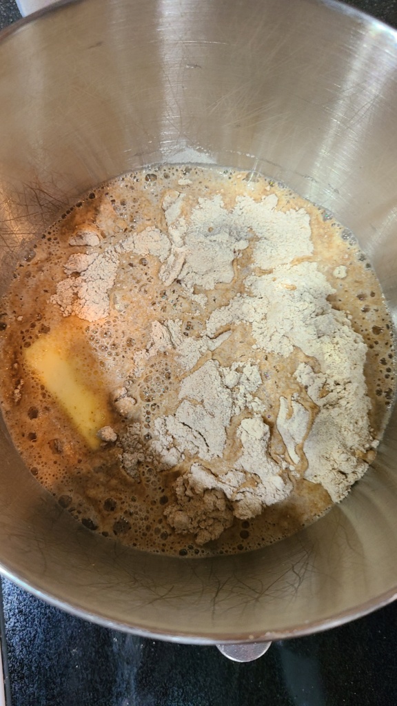 A large bowl with a water and yeast mixture, with flour and butter