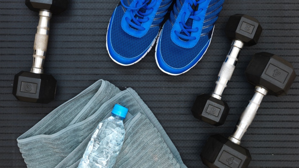 Dumbbells, workout shoes, and a bottle of water on a towel