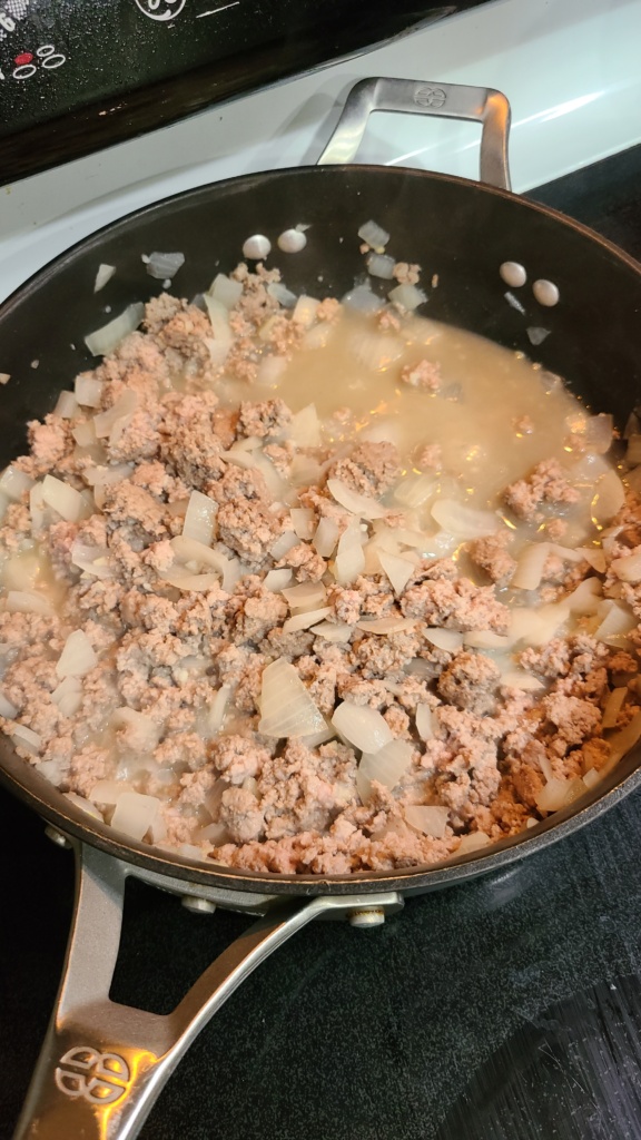 A large pan with cooked ground turkey and onions