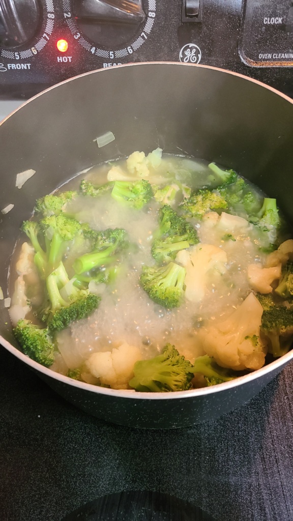 A large pot with boiling ingredients for broccoli cheddar soup