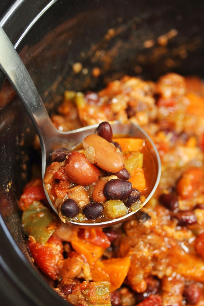 Cooked chili in a slow cooker, and a ladle scooping out chili