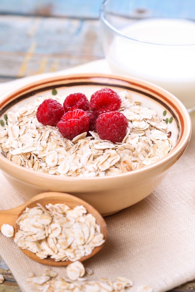 A bowl of dried rolled oats, topped with raspberries