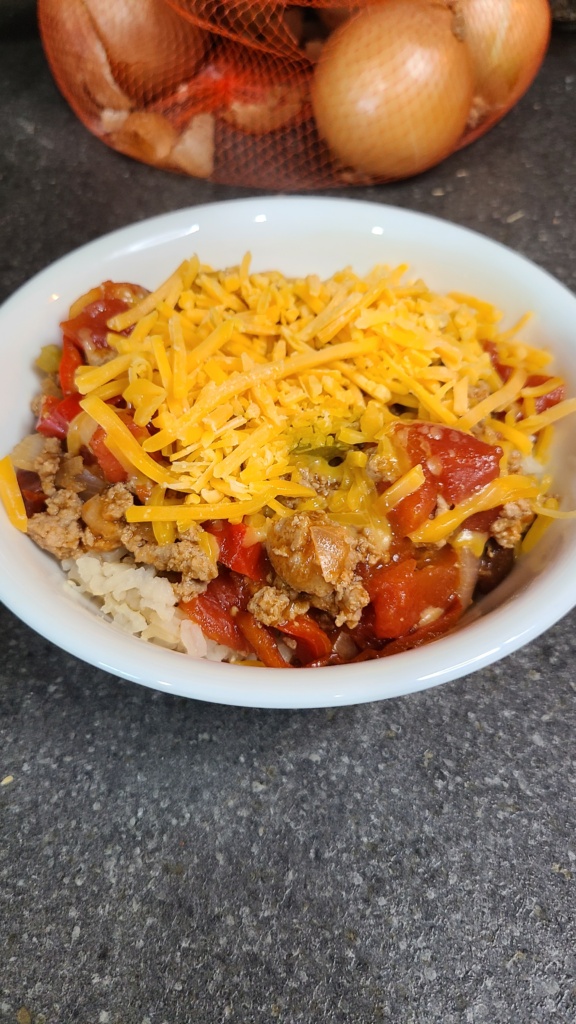A bowl of chili topped with shredded cheddar
