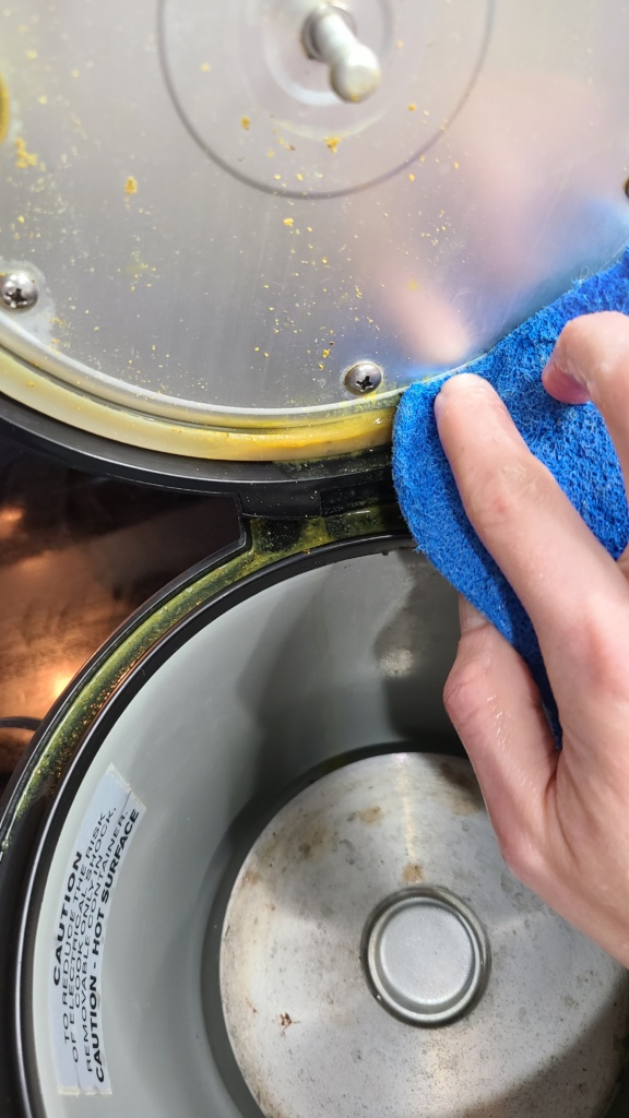 A sponge cleaning the rubber ring of a rice cooker lid