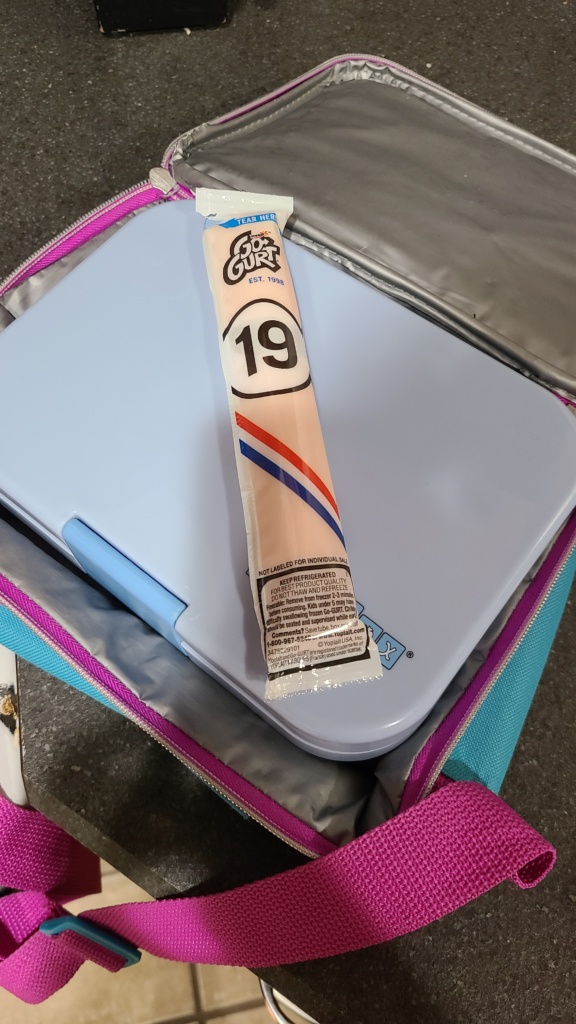 A tube of Gogurt on top of a lunch box