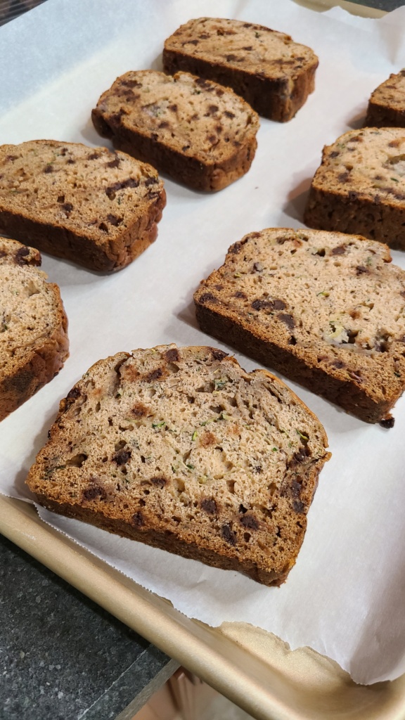 Slices of zucchini bread on a baking sheet lined with parchment paper
