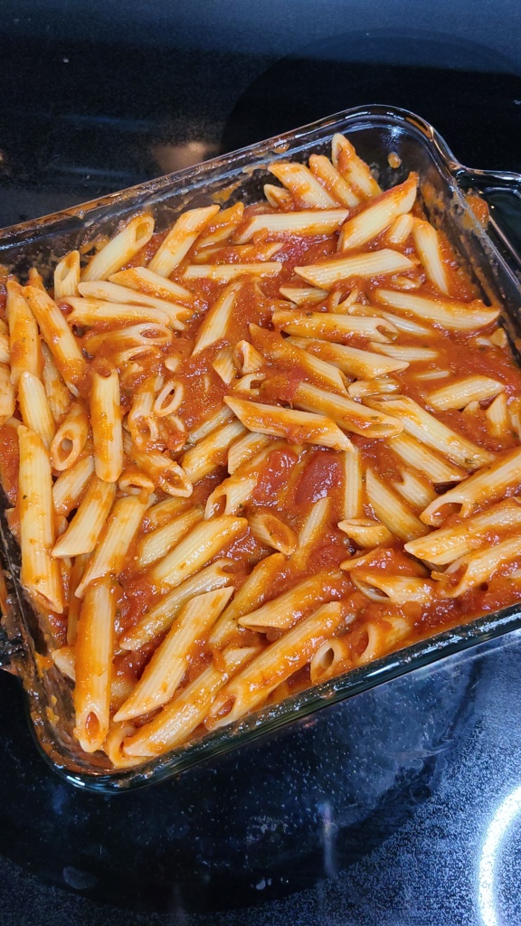 An 8x8 casserole dish with cooked pasta and marinara sauce mixed together
