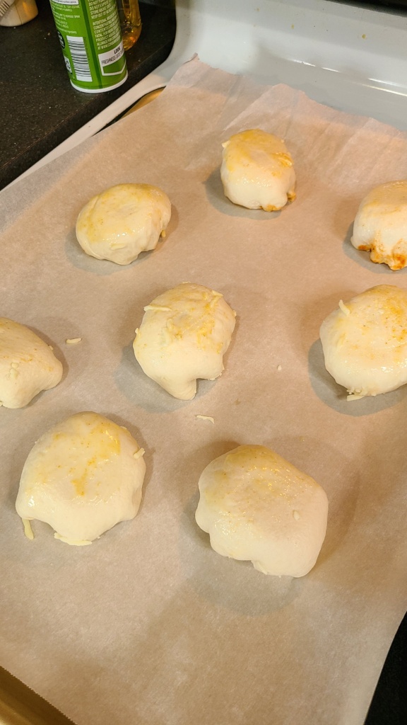 A baking sheet lined with parchment paper and topped with unbaked meatball bombs