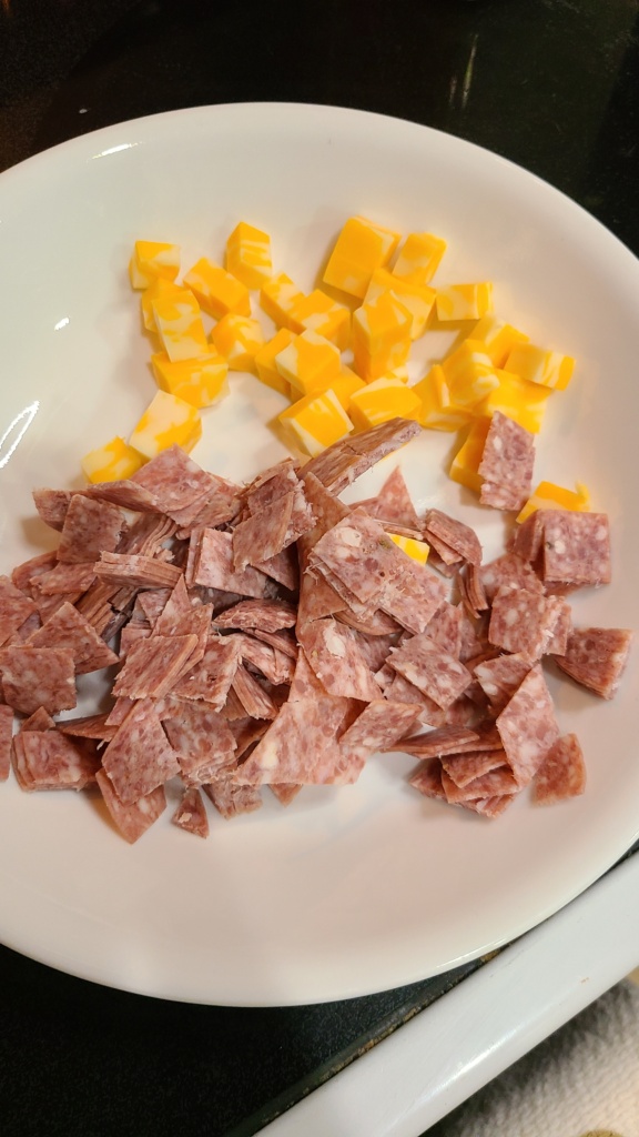 A bowl filled with cubed Colby Jack cheese and diced salami