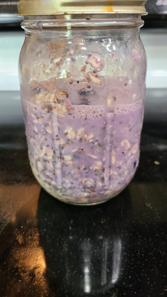 A Mason jar filled with mixed ingredients for blueberry overnight oats
