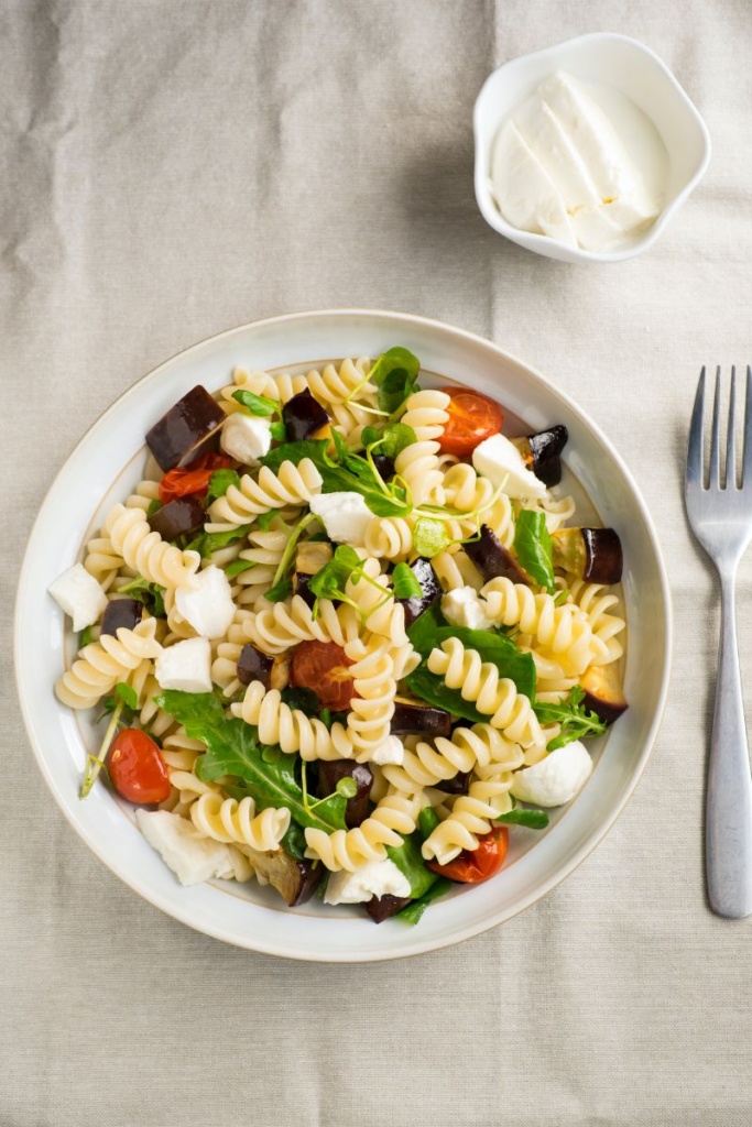 A bowl of pasta salad, a fork sitting next to it