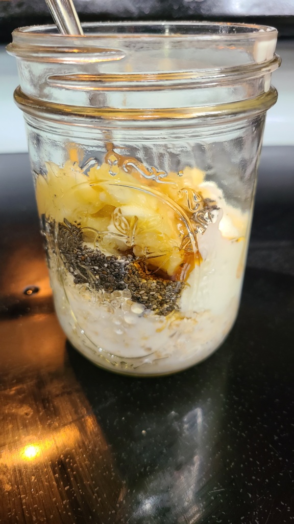 A Mason jar filled with unstirred ingredients for banana peanut butter overnight oats