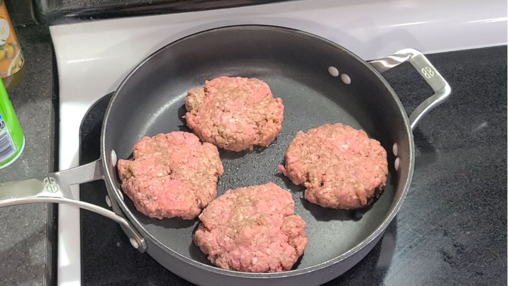 Burger patties cooking in a skillet
