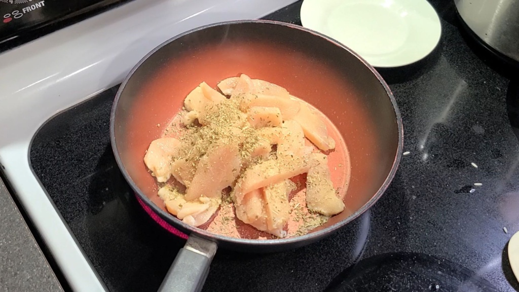 Slices of raw chicken cooking in a skillet