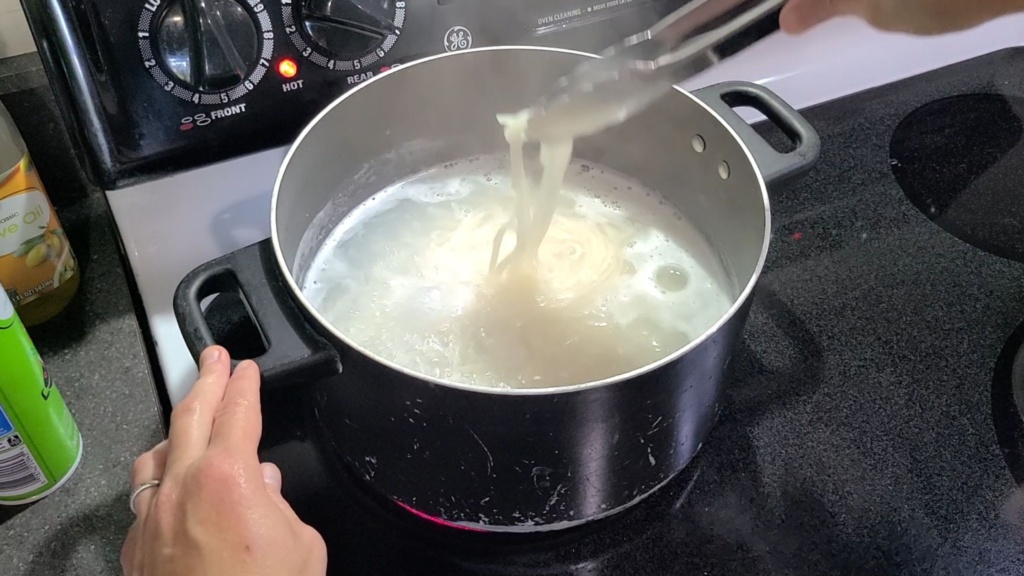 A boiling pot of water. Rice noodles are being cooked.